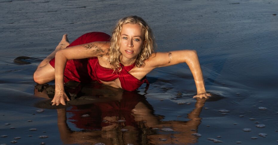 Skylar Temple Singer on the shoreline at golden hour, wearing red