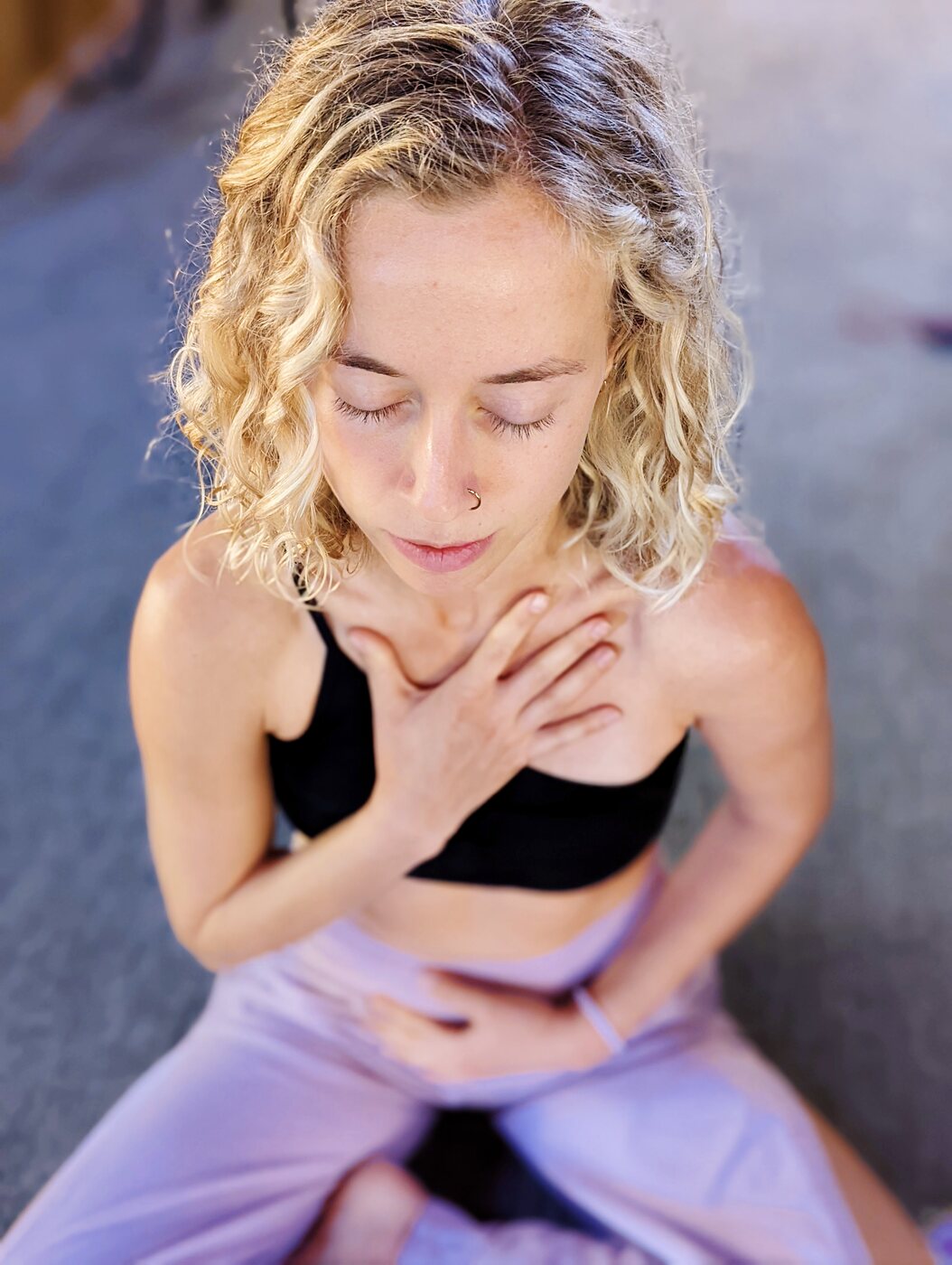 Skylar with hand at her throat, eyes closed, in soft lavender light
